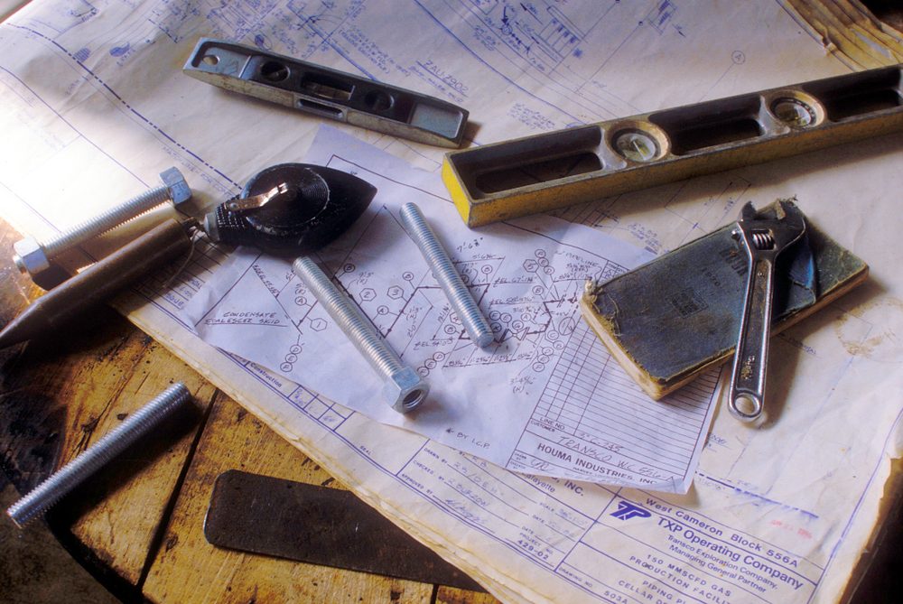 Piping drawings with level, wrench and bolts on a workbench