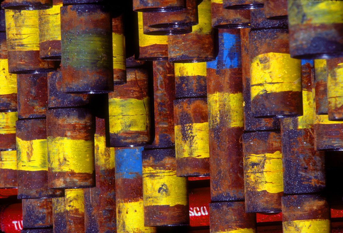 Weathered pipe ends painted yellow, blue and red, stacked in a pipe yard